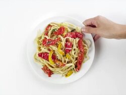 CU Woman hand entering setting down round white plate with pasta linguine, red pepper salad / Omaha, Nebraska, United States Stock Footage
