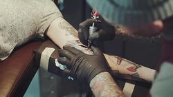 Tattoo artist tattooing young woman Stock Footage
