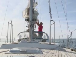 MS Pensioner ties down sail on his sailboat in sun on calm day / Wismar, Mecklenburg-Vorpommern, Germany Stock Footage