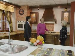 WS salesman and mature couple in kitchen showroom with traditional furniture; they discuss the exhibit and laugh Stock Footage