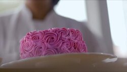 Pastry chef decorates pink cake with white frosting Stock Footage