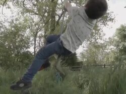 Little Boy Sitting On Rope Swing In The British Countryside Stock Footage