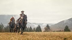 SLO MO Two cowboys and cowgirl galloping across a meadow Stock Footage
