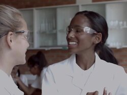 MS Two school girls looking together at blue liquid in beacon Stock Footage
