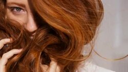 Woman holds her red hair to her face covering her smile Stock Footage