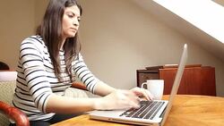 Young woman using laptop and drinking coffee. Stock Footage