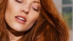 Womans red hair sways in the breeze covering part of her face Stock Footage