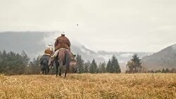 SLO MO Cowgirl riding across mountain with two cowboys Stock Footage