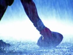 OVEREXPOSED slow motion close up PAN football player snaps ball into play, second player runs with ball in rain Stock Footage