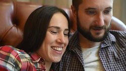 young couple sitting on sofa and using gadgets Stock Footage