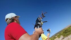 Two male pilots controlling drone takeoff on sunny hilltop Stock Footage