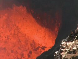 Man sits on ledge overlooking erupting lava lake, Marum Volcano, Ambrym Island, Vanuatu Stock Footage