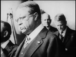 B/W 1900s close up Theodore Roosevelt surrounded by people talking to someone offscreen Stock Footage