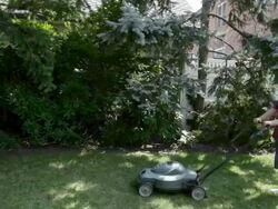Boy mowing grass with lawnmower Stock Footage