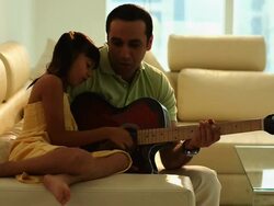 Man playing a guitar with his daughter  Stock Footage