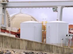 WS ZO San Onofre nuclear power plant behind sea wall and San Onofre State Beach where woman walks her dog / Pendleton, California, USA Stock Footage