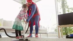 Superhero father and daughter vacuuming in living room Stock Footage