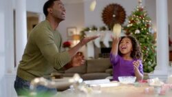 Young girl laughs as she tosses cookie dough into the air with her dad (dolly-shot) Stock Footage