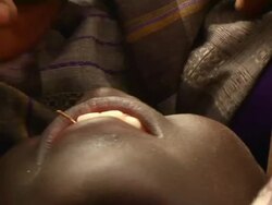 Man cutting boy's tooth during ritual Stock Footage