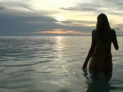 Woman silhouette in front of the ocean; sunset time Stock Footage