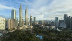 Thin clouds move over the Petronas Twin Towers and a nearby park in the Kuala Lumpur City Center. Stock Footage