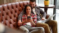 young couple sitting on sofa and using gadgets Stock Footage