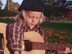 MS Shot of young boy learns to strum guitar in park / Beaverton, Oregon, United States Stock Footage