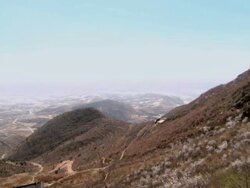 Overlooking a Chinese village from a mountainside, then panning right, up the mountain towards the Great Wall of China. Stock Footage