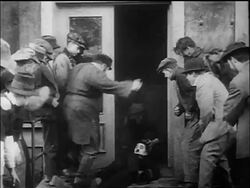 B/W 1917 man (Henry Bergman?) picking up dazed policeman Charlie Chaplin + dropping him into manhole Stock Footage