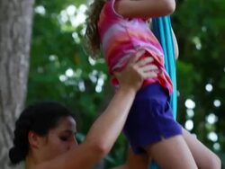 MS TU TD TS Woman holds little girl as she climbs up fabric hanging from large tropical trees and pulls herself up with her feet / Montezuma, Puntarenas, Costa Rica Stock Footage