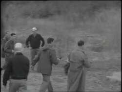 An F.B.I. agent speaks through a megaphone to a suspect in a building and the man exits and puts his hands against the wall. News Clip