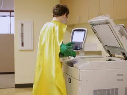 MS Wearing green outfit and yellow cape, superhero mischievously sneaks into copy room and makes copy of his face before sneaking back out / Seattle, Washington, United States  Stock Footage