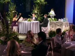 DOLLY WS guests enjoying themselves at their tables, with bride, groom, best man, and maid of honor at wedding table on stage Stock Footage