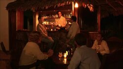Two men greet each other and sit at a bar to smoke cigars. Stock Footage