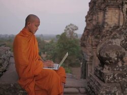 MS, PAN A Buddhist monk types on a laptop computer on top of an ancient temple in Angkor Wat / Siem Reap, Cambodia Stock Footage