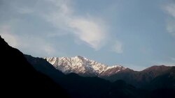 Pan shot of snow capped Himalayan Mountains at sunset with wispy clouds. Stock Footage