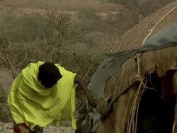 Afar woman fixing straw on hut Stock Footage