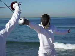 A man and woman fencing on the beach. - Slow Motion Stock Footage