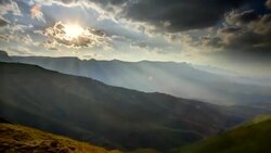 Sunbeams filter through racing clouds as they drift over the Drakensberg Mountains in South Africa. Stock Footage