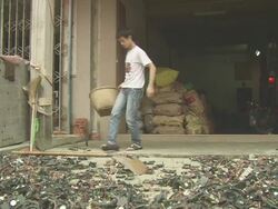 WS Shot of boy shovels old electronics components into basket / Shenzen, China Stock Footage
