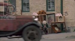 Two women and a boy sitting on the street with belongings looking cold, 1930s - reenactment Stock Footage