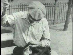 A homeless man sews a tear in his clothing. News Clip