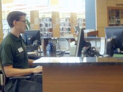 MS TS librarian working at computer terminal at help desk in public library / Rancho Mirage, California, USA Stock Footage