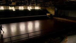 Sunlight illuminates a dark basketball court as two athletes high-five as they walk off the court. Stock Footage