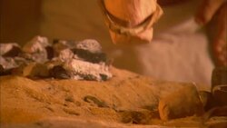 A man heats a solid substance in a clay pot. Stock Footage