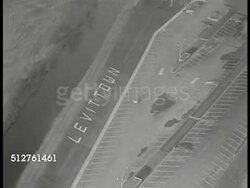 1953: LEVITTOWN, PENNSYLVANIA: AERIAL: Levittown lettering on ground next to parking. WS Completed homes in section of planned community. TD WS Homes & streets. WS Open area w/ building footprint blocked out. Postwar, suburb, Lifestyle, affordable Instructional Video