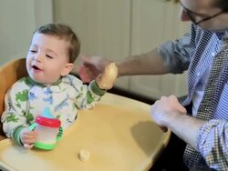 Baby boy sitting in high chair eating breakfast with father Stock Footage