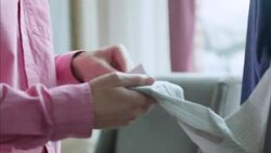 Young man holds up shirtsleeve to look at price tag in clothing store Stock Footage