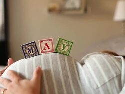 A pregnant women using blocks to spell the month of MAY on her stomach. Stock Footage