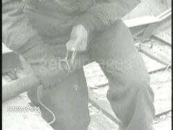 1950: KOREAN WAR: SOUTH KOREA: VS United States Marine preparing explosives on bridge, tying rope around pipe bomb, explosion along field. Instructional Video